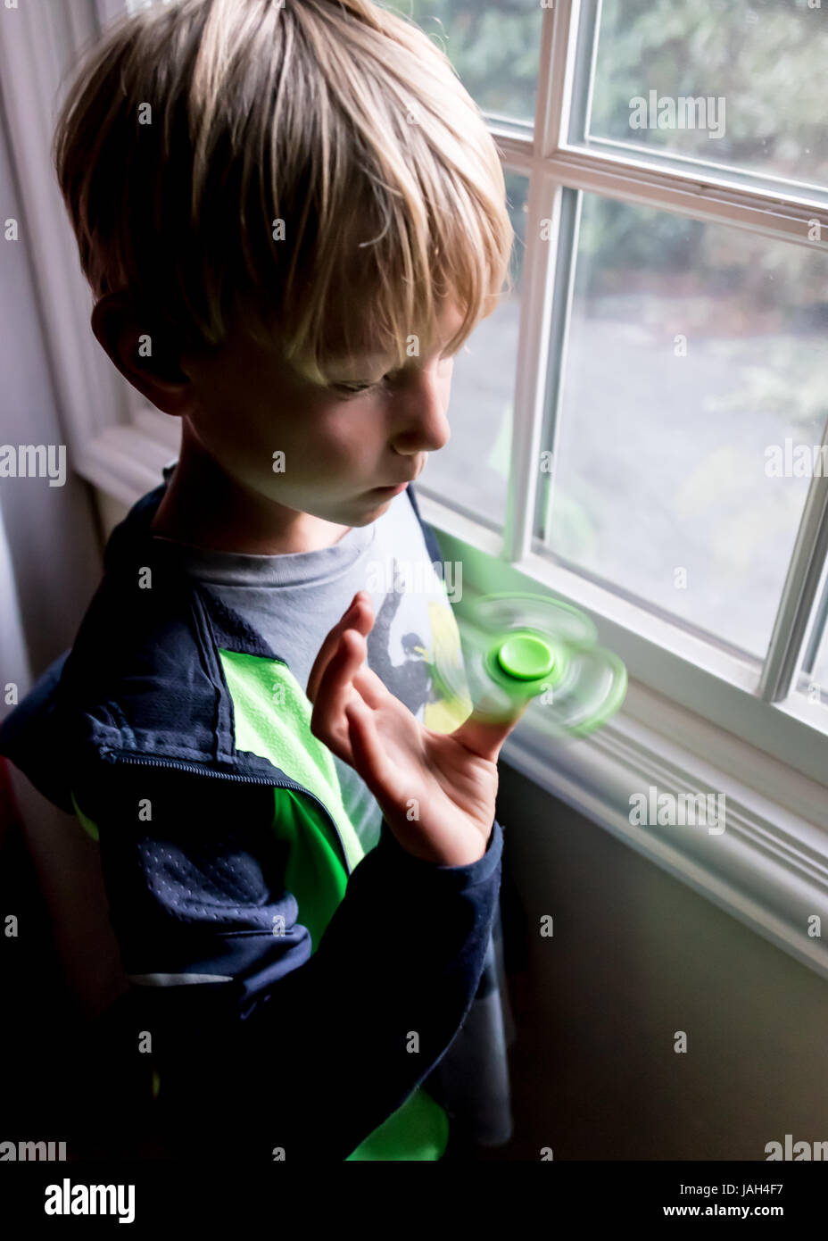 Ein Junge spielt mit einem Fidget Spinner zu Hause das umstrittene Stress Relief Spielzeug gefunden, einige kribbelig oder autistischen Kindern helfen Konzentrat in der Schule Stockfoto