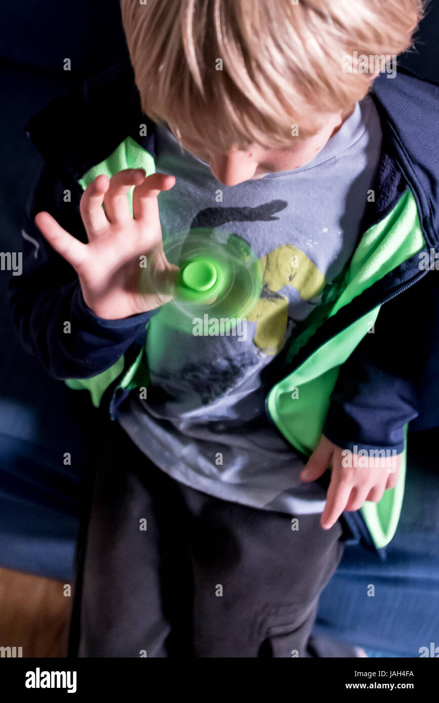 Ein Junge spielt mit einem Fidget Spinner zu Hause das umstrittene Stress Relief Spielzeug gefunden, einige kribbelig oder autistischen Kindern helfen Konzentrat in der Schule Stockfoto