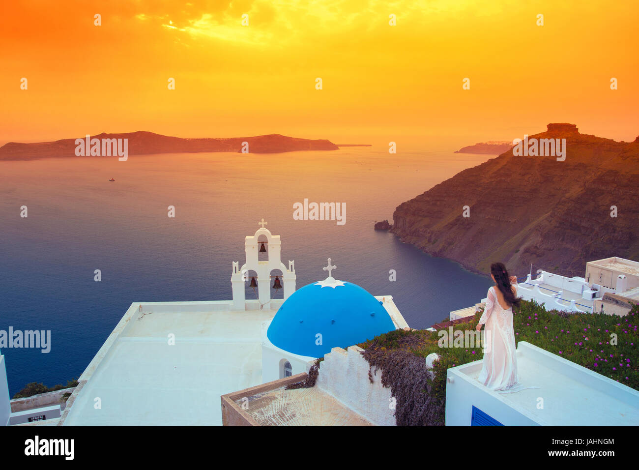 Brillante Sonnenuntergang in Fira mit einer Kirche und einem Braut auf einem Dach, Santorini, Griechenland. Stockfoto