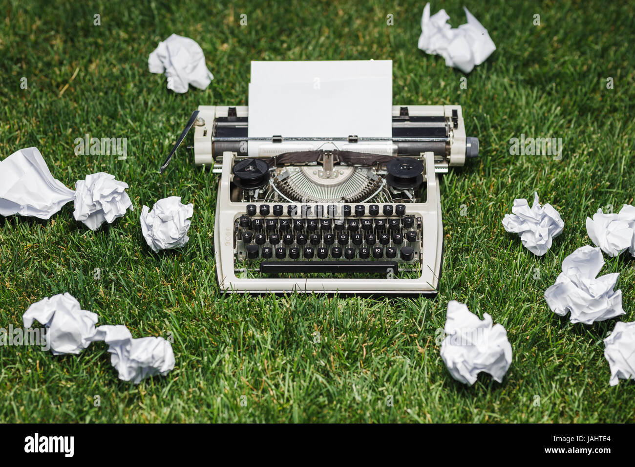 Foto von alten Schreibmaschine auf dem grünen Rasen mit einem Blatt Papier. Stockfoto