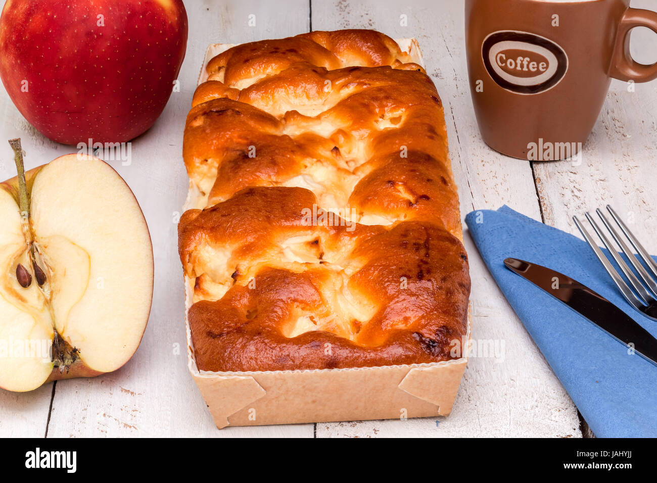 Ein länglicher Apfelkuchen mit Kaffee und Besteck Stockfoto