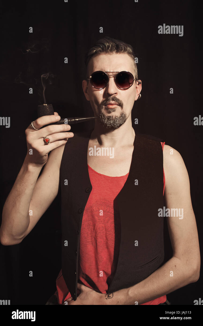 Porträt eines Mannes, raucht eine Pfeife auf schwarzem Hintergrund Stockfoto