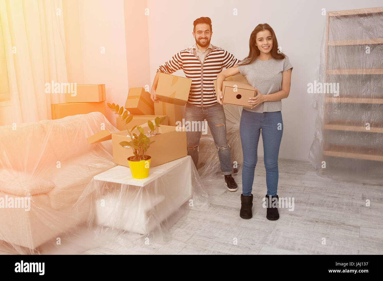 Glückliches junges Paar auspacken oder Kisten packen und der Umzug in ein neues Zuhause. Stockfoto