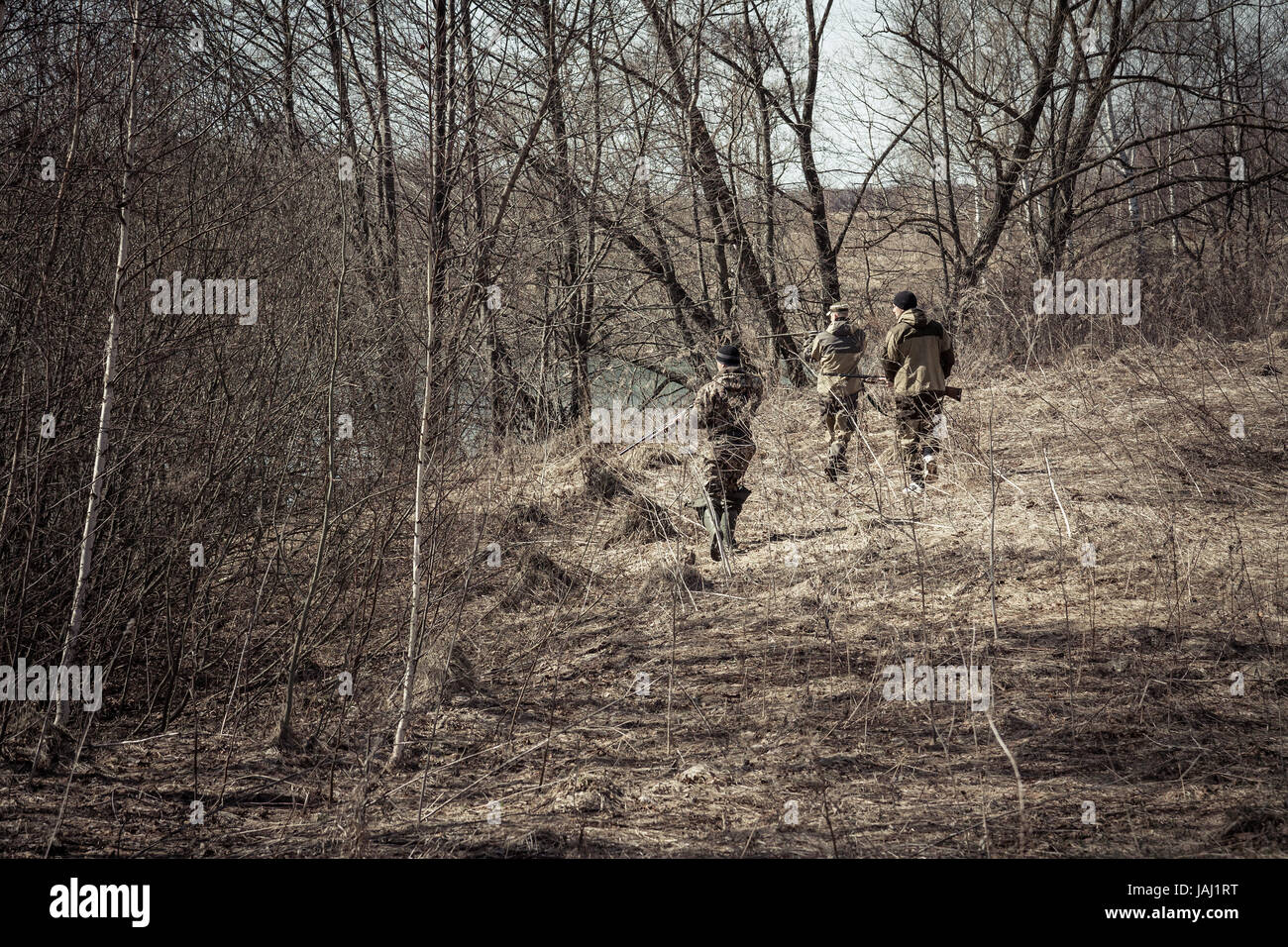 Jagdszene mit Jägern in Tarnung während der Jagdsaison im Frühlingswald mit trockenen Blättern zu stehlen Stockfoto