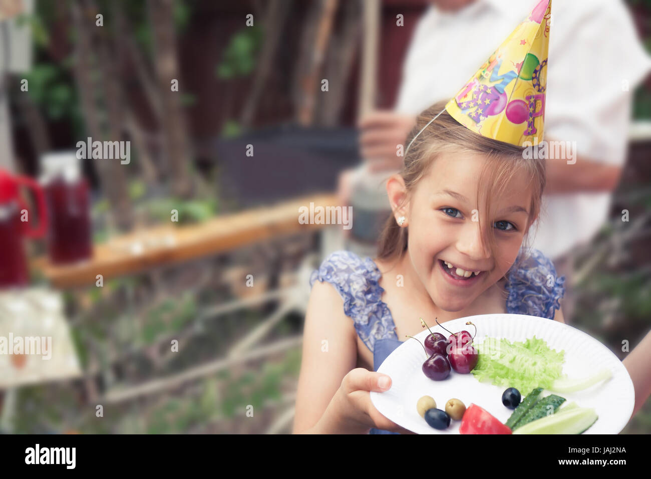 Glücklich lächelnde Kind Mädchen behandeln, gesunde Ernährung mit Teller mit Gemüse im Hinterhof-Geburtstags-party Stockfoto