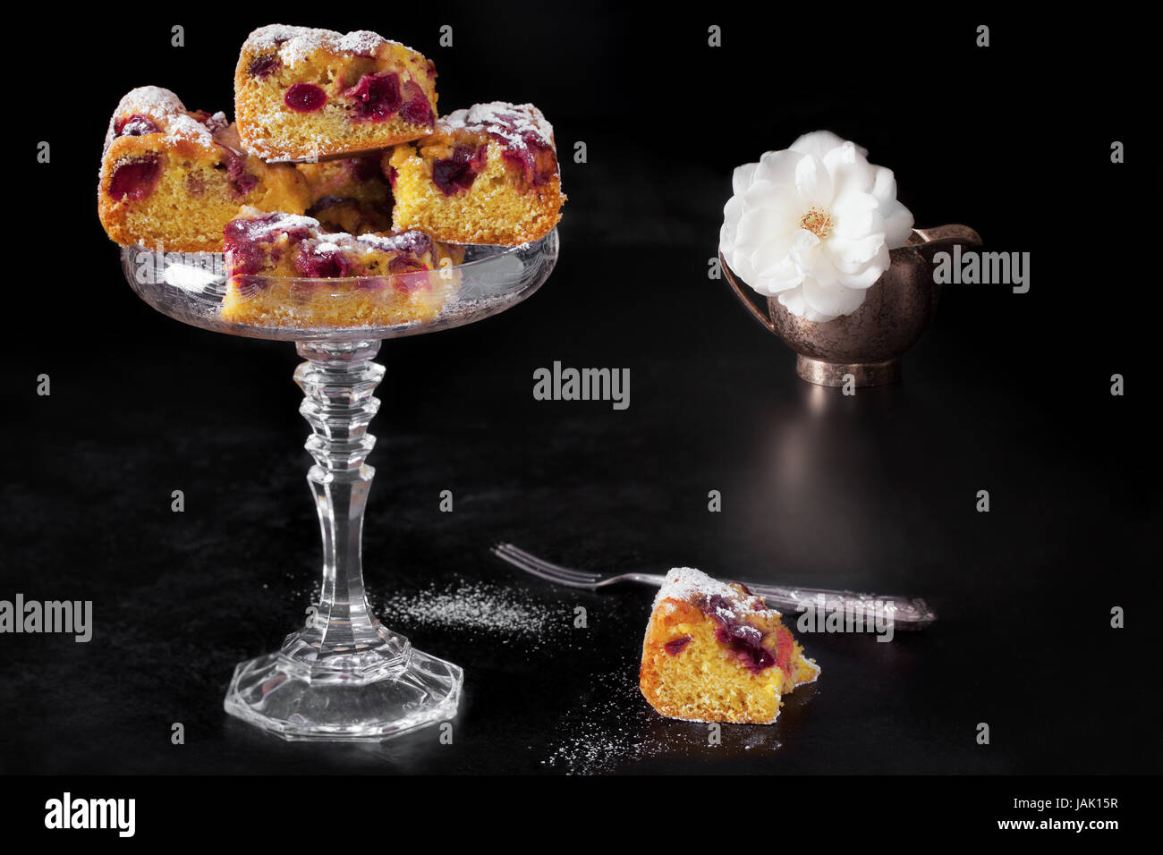 Kuchen mit Stücken von Kirsche Plumcake auf schwarzem Hintergrund stehen. Stockfoto