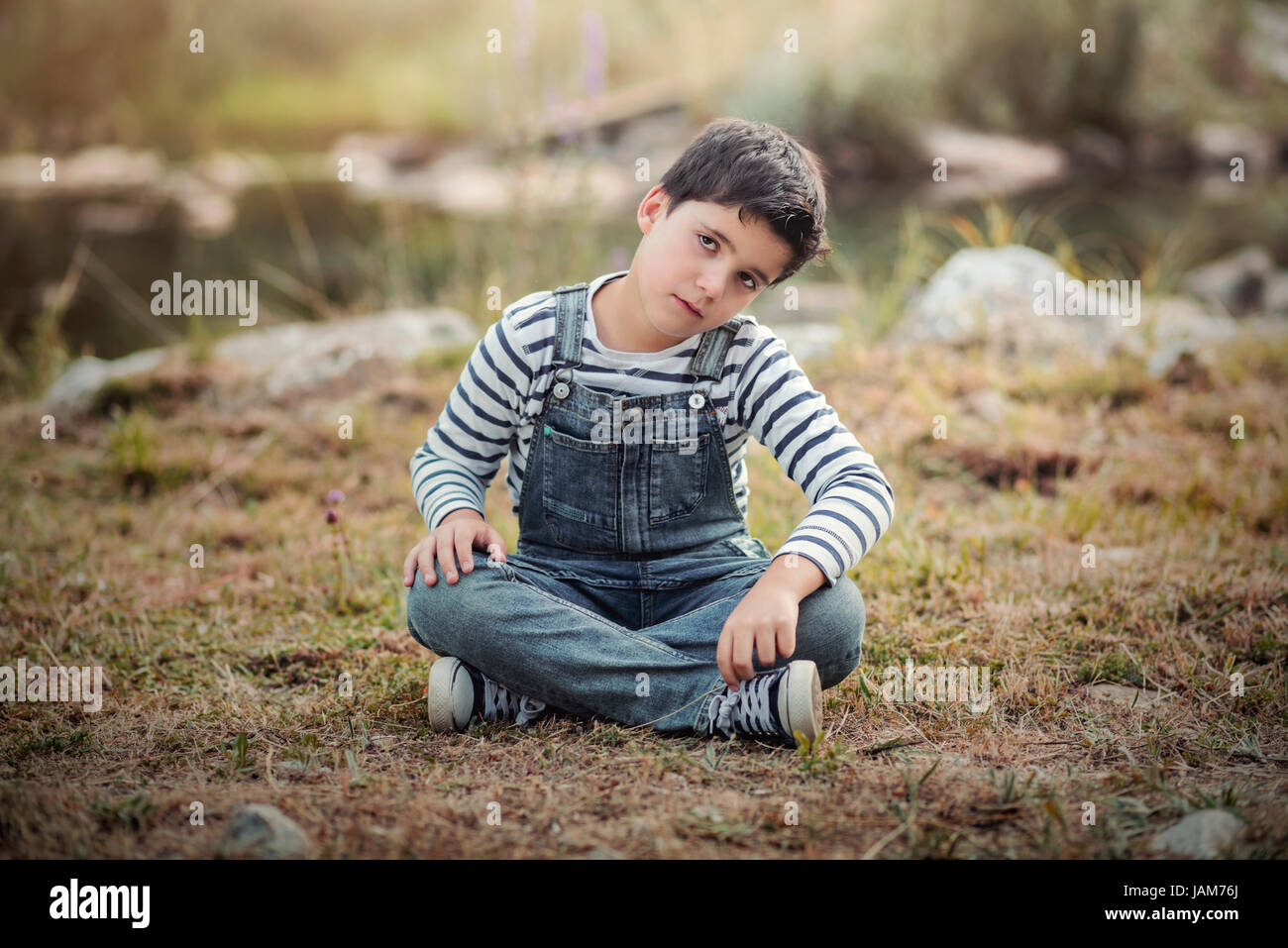 Traurige Junge sitzt im Feld Stockfoto