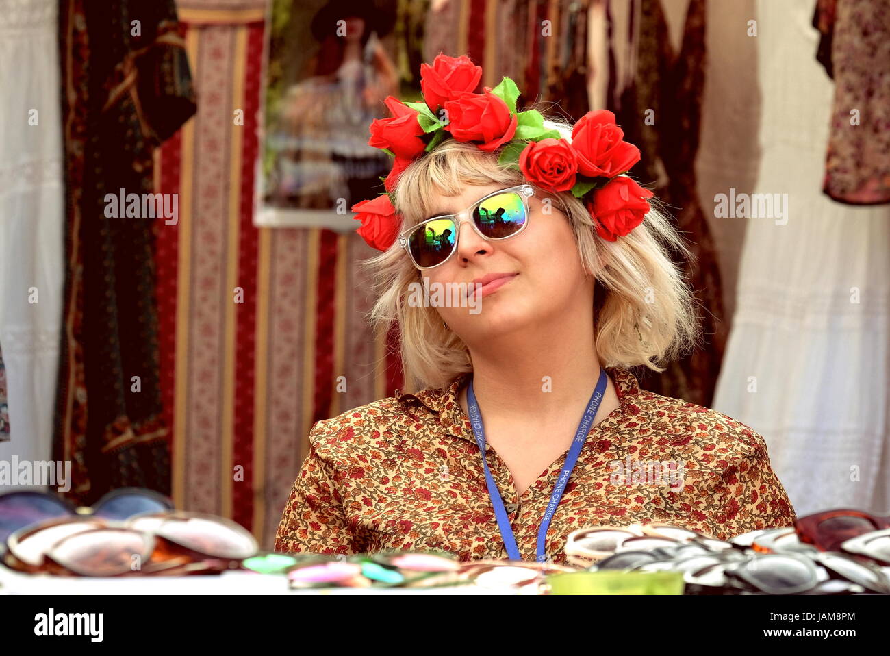 Frau mit roten Rosen im Haar der 1950er Jahre Kleid Retro-Kleidung, Vintage-Artikel verkaufen Antiquitäten an Outdoor-Festival Marktstand, Stockfoto