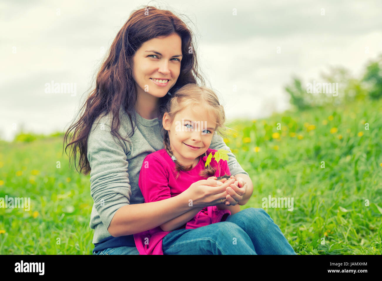 Mutter und Tochter, die kleine grüne Pflanze in den Händen halten Stockfoto