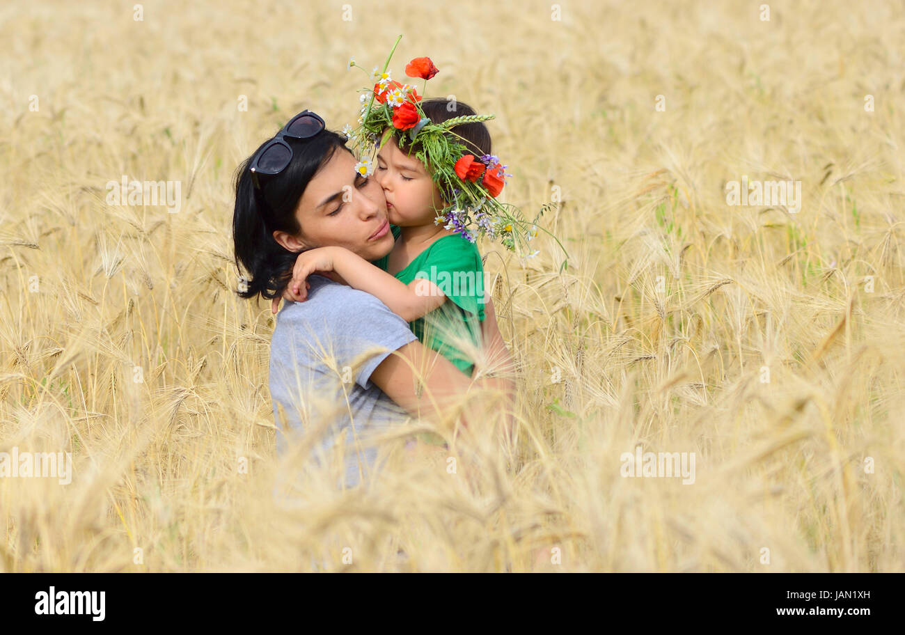 Glückliche Familie auf einer Sommerwiese. kleine Mädchen Kind Baby Tochter umarmen und küssen Mutter Stockfoto