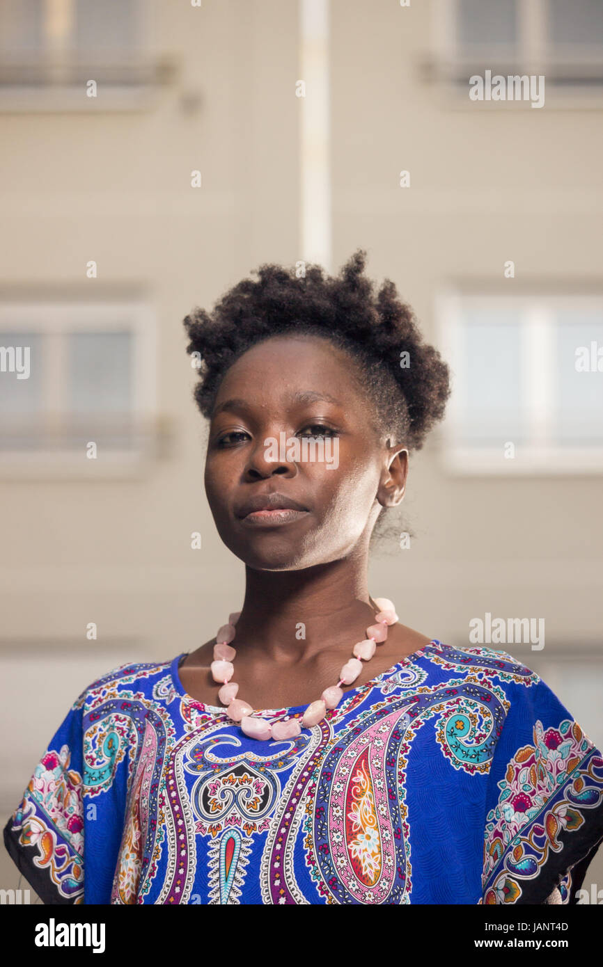 ein, junge Erwachsene, schwarze afrikanische amerikanische Frau, 20-29 Jahren, ernsten Ausdruck, Kopf und Schultern Schuss, Gebäude hinter, auf Kamera, niedrigen ang Stockfoto