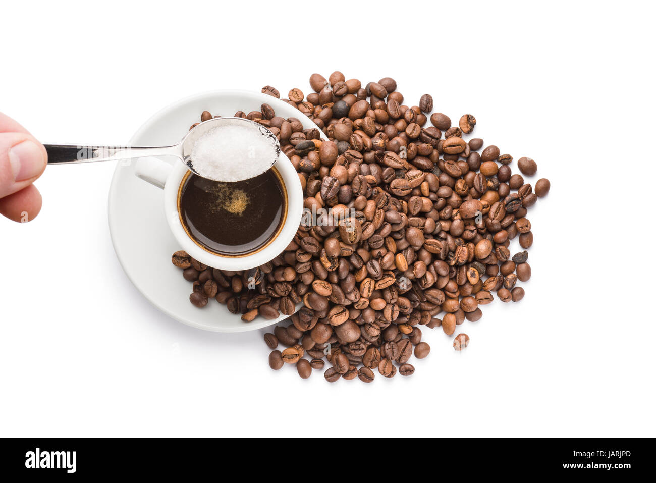 strömenden Zucker mit einem Teelöffel auf Tasse Kaffee auf weißem Hintergrund Stockfoto