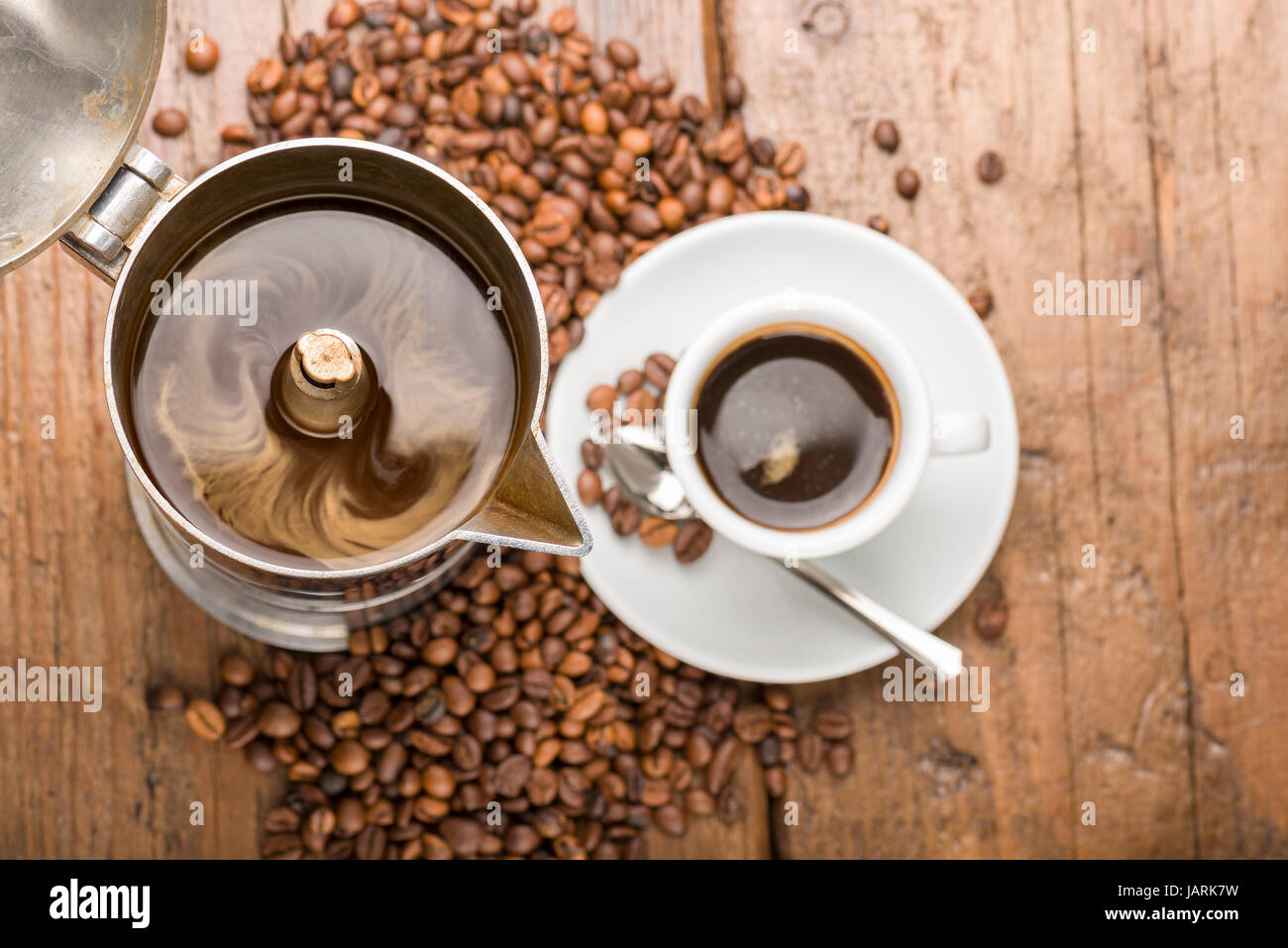 Kaffeekanne und Tasse Kaffee mit Kaffeebohnen auf Holztisch Stockfoto