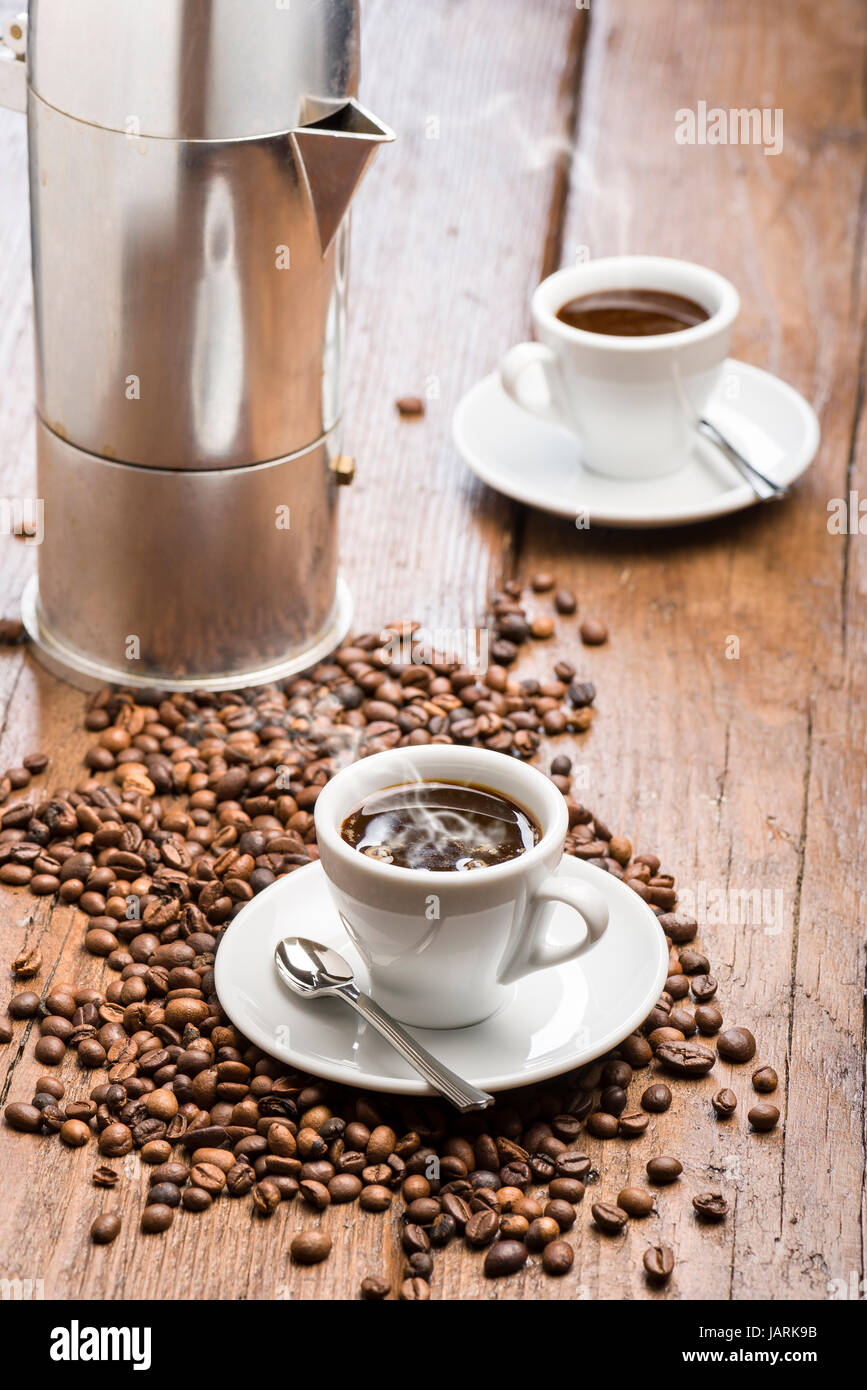 Tasse Kaffee mit Kaffeekanne und Kaffeebohnen auf Holztisch Stockfoto