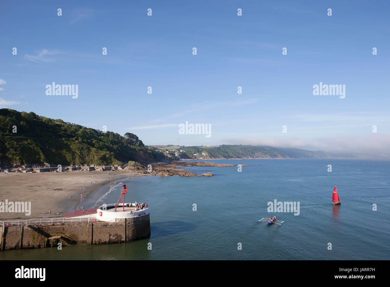 Ein rotes segelte Schlauchboot und ein pilot Gig begeben Sie sich ins Meer wie Nebel über die Klippen in Looe, Cornwall rollt. Die Banjo-Pier und Strand stehen im Vordergrund. Stockfoto