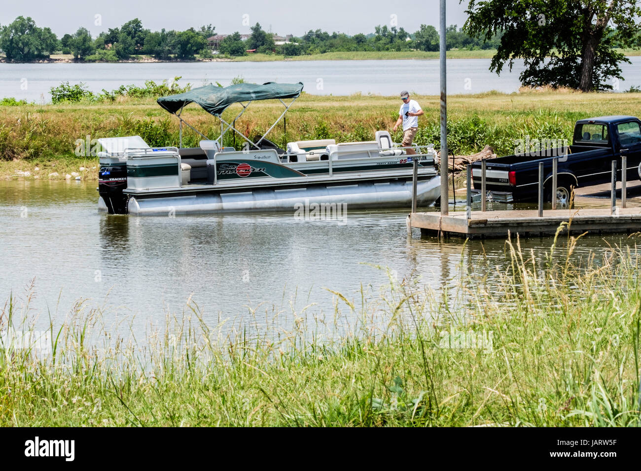 Ein kaukasischer Mann lädt ein Ponton-Boot auf einen Bootsanhänger nach dem Angeln auf Overholser See in Oklahoma City, Oklahoma, USA. Stockfoto