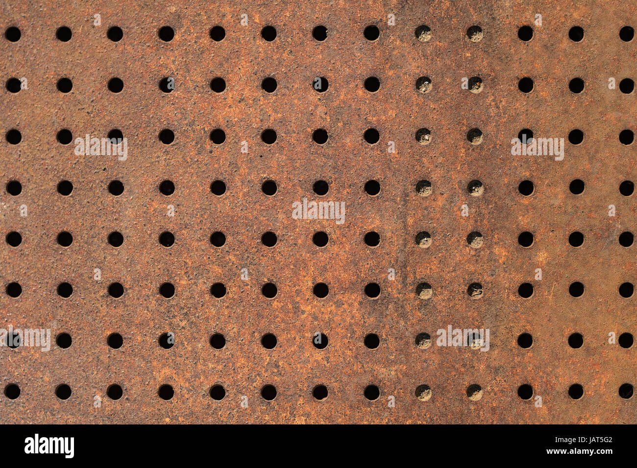 Rostige Textur aus perforiertem Metall. Regelmäßige Muster der Bohrungen in ein Blech. Rostiges Eisen Hintergrund mit Löchern Stockfoto