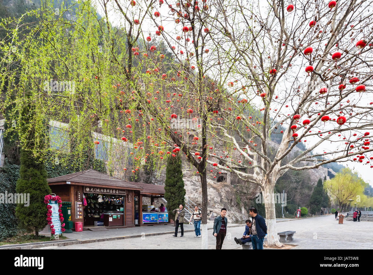 LUOYANG, CHINA - 20. März 2017: Touristen in der Nähe von Baum mit chinesischen roten Laternen auf West Hill von Longmen Grotten (Longmen Shiku, Dragon es Gate Grotten, Stockfoto