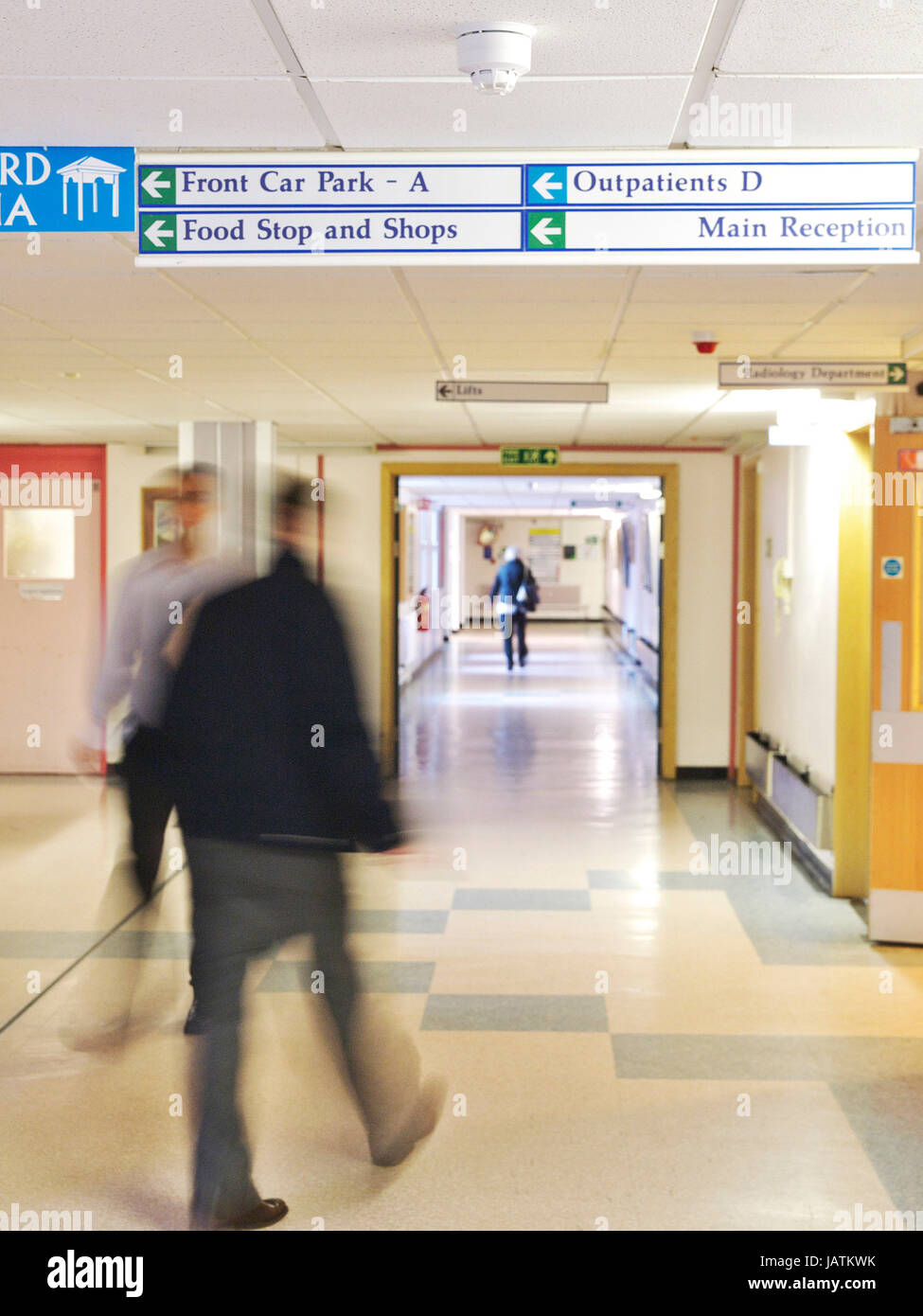 Patienten und Mitarbeiter Spaziergang entlang dem Flur in einer geschäftigen NHS District Hospital Stockfoto