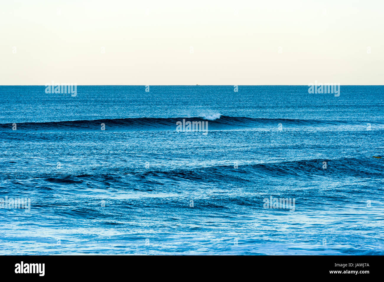 Eine saubere Welle schält zum Strand in der Dämmerung. Stockfoto