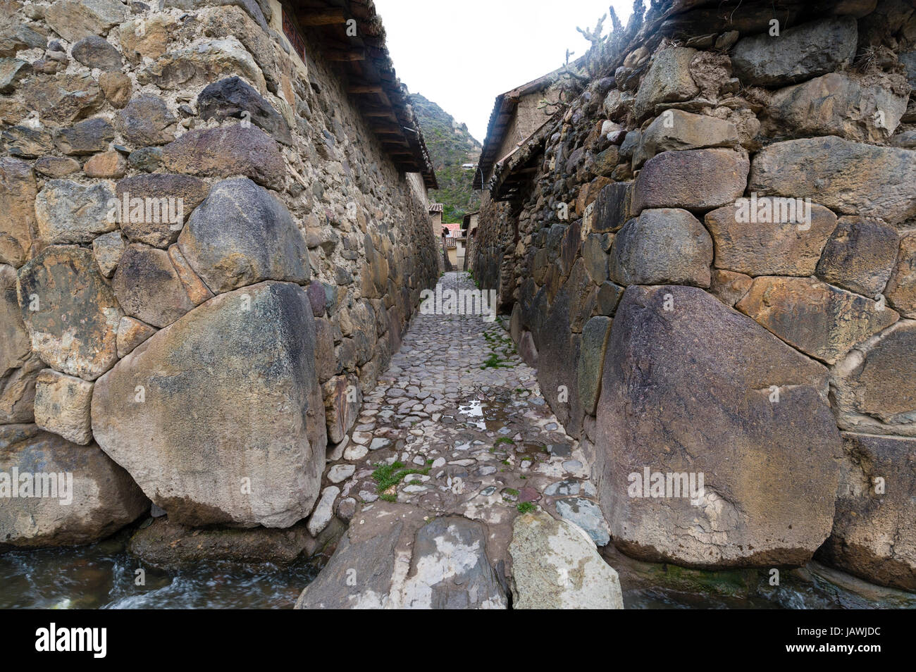 Ein Bewässerungskanal in einem Dorf Lane mit Steinen gepflastert und gesäumt von hohen Inka Trockenmauern. Stockfoto