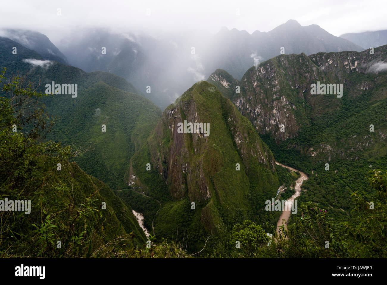 Steile Bergen mit Wald bedeckt und gezackten Gipfeln über einen gewundenen Fluss in den Anden. Stockfoto