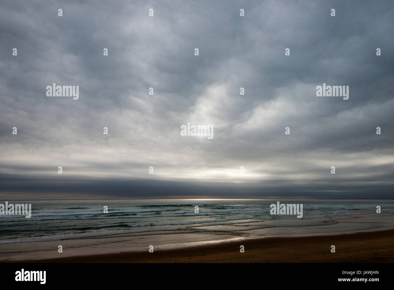 Graue Wolken hängen über einem verlassenen Strand an einem stürmischen Tag. Stockfoto