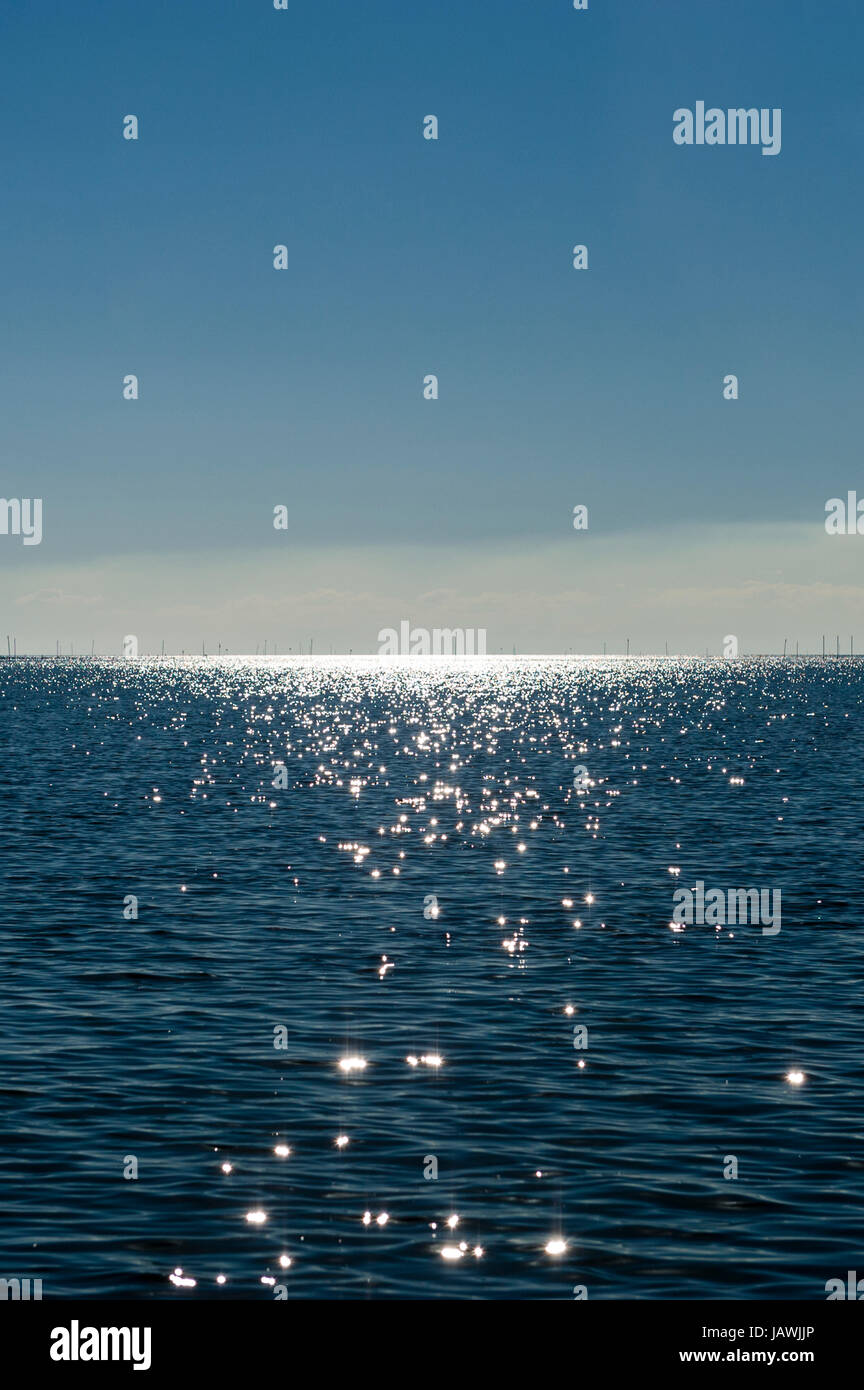 Gefleckte Sonnenlicht glitzern von der Oberfläche eines ruhigen Ozeans. Stockfoto