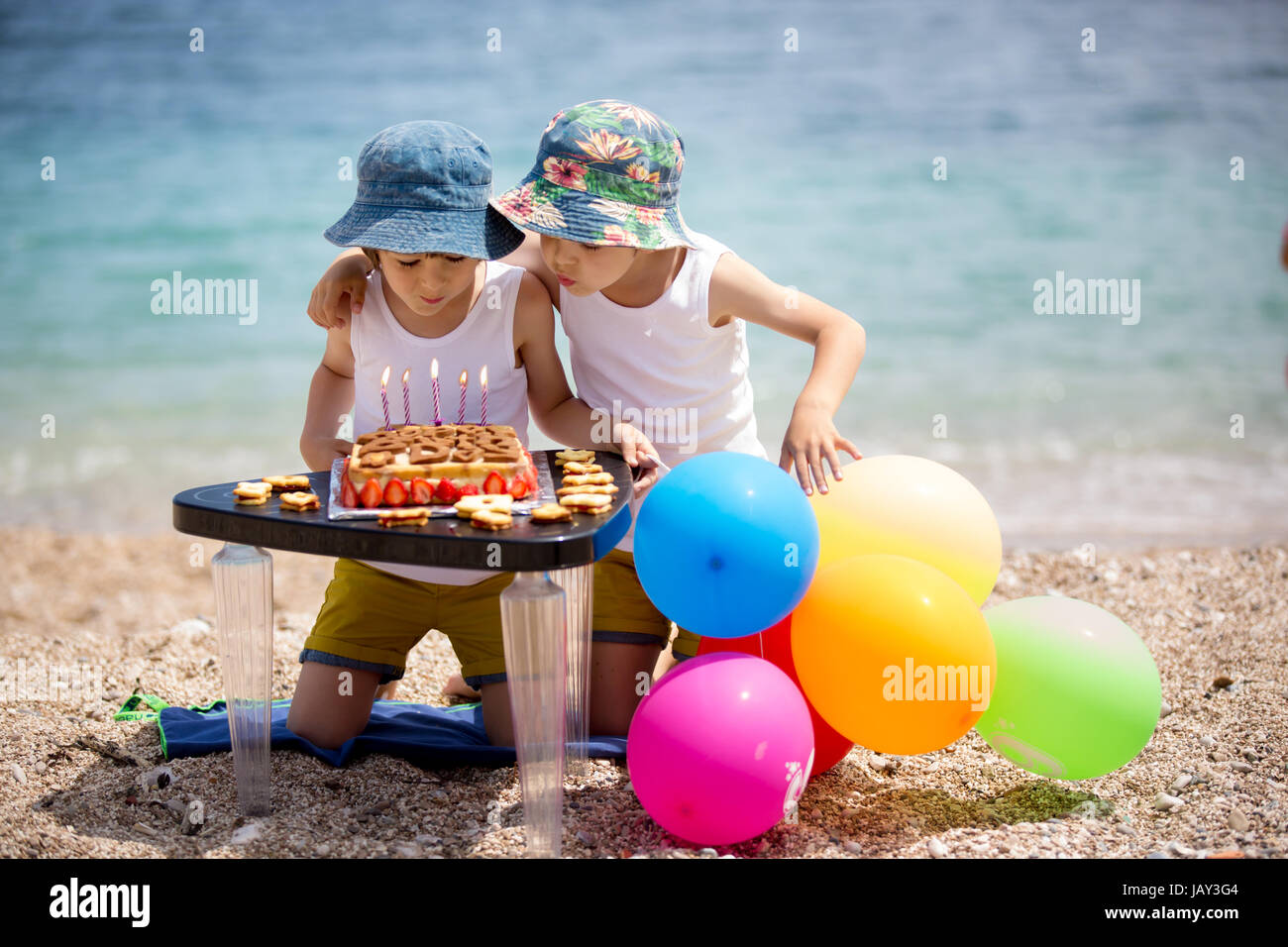 Süße kleine Kinder, zwei jungen, feiert ihren sechsten Geburtstag am Strand, Kuchen, Luftballons, Kerzen, Cookies. Kindheit-Glück-Konzept Stockfoto