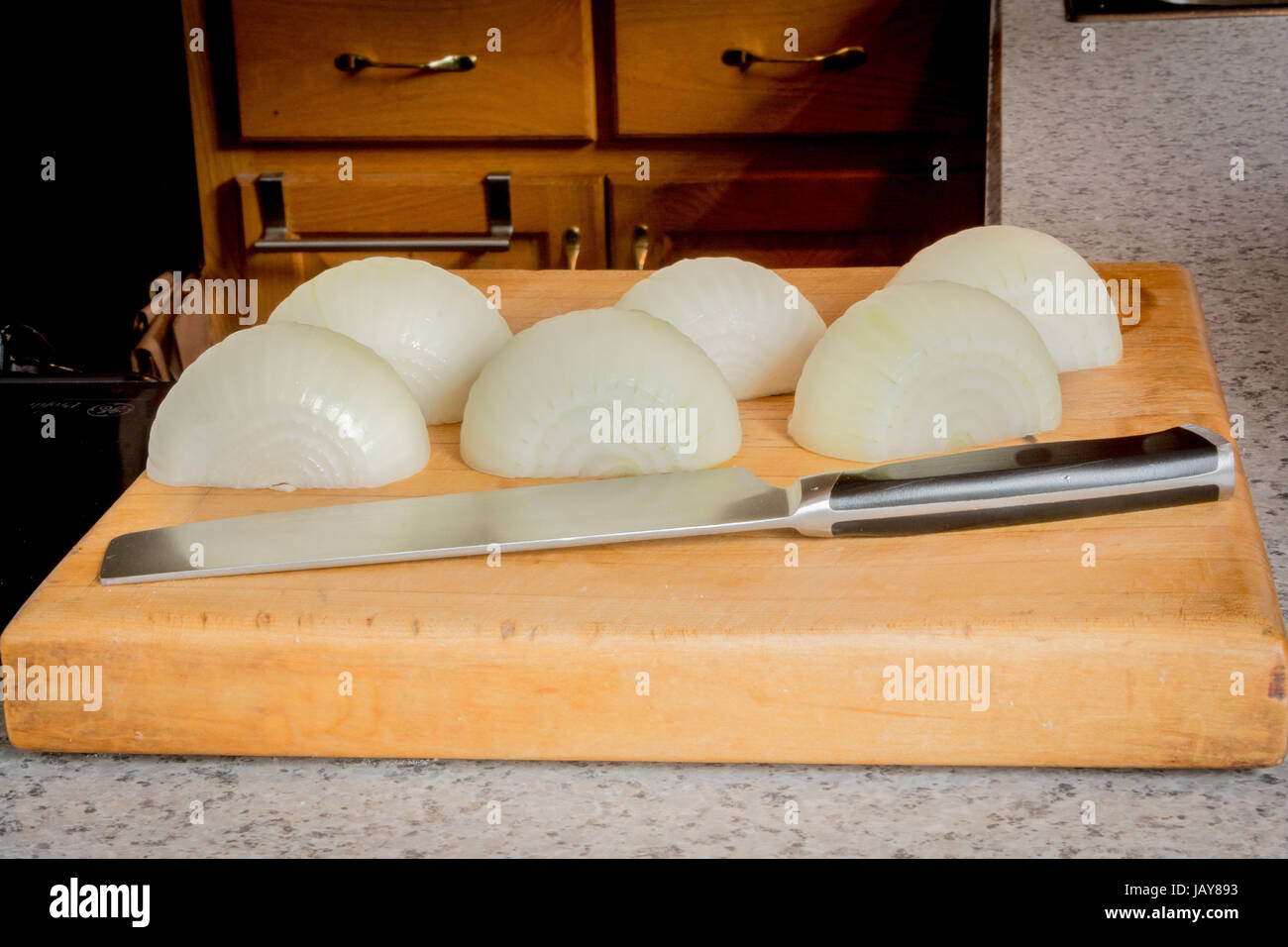 Geschälte Zwiebeln mit einem Messer auf ein Schneidebrett. Stockfoto