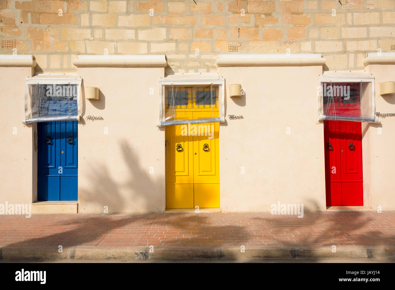 Drei blau hell farbige gelbe und rote Haustüren auf ein Apartment Gebäude in der Fischerei Hafen von Marsaxlokk Malta Stockfoto