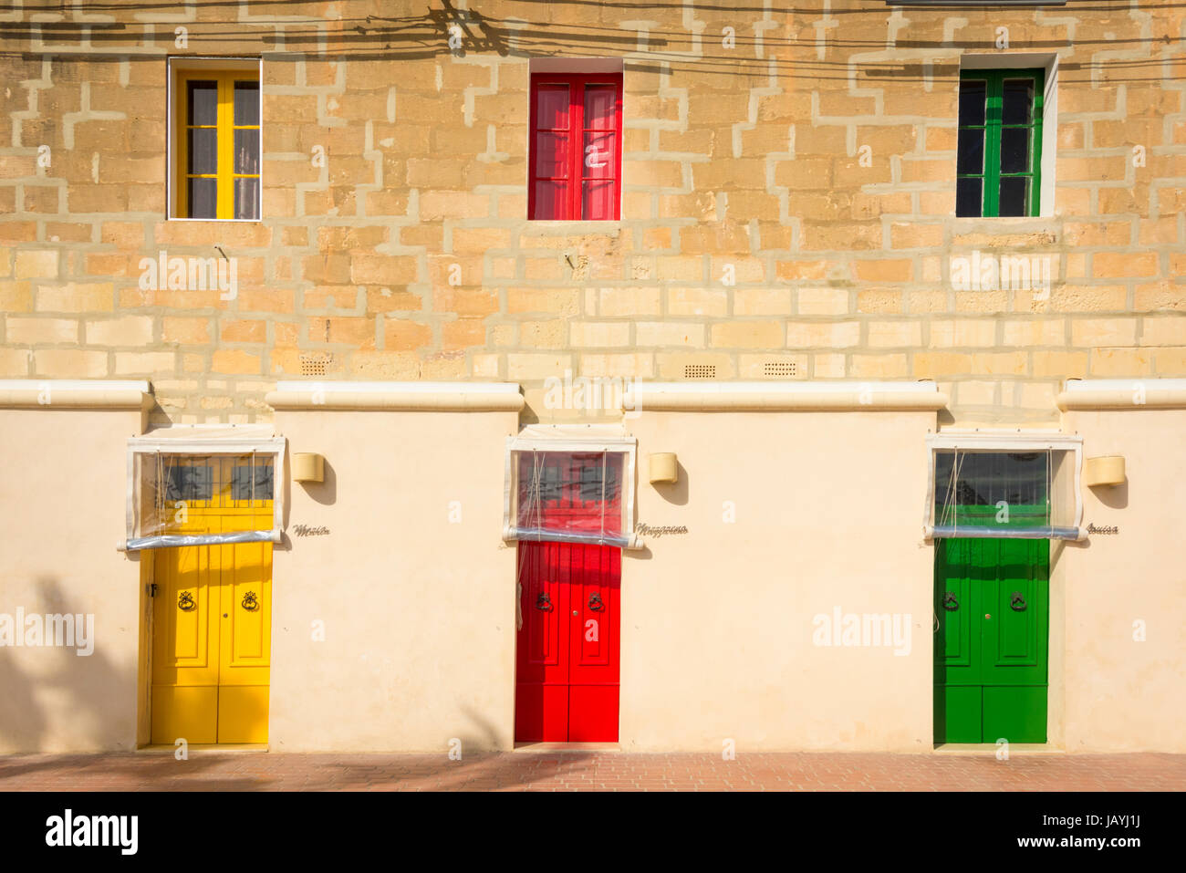 Drei blau hell farbige gelbe und rote Haustüren auf ein Apartment Gebäude in der Fischerei Hafen von Marsaxlokk Malta Stockfoto