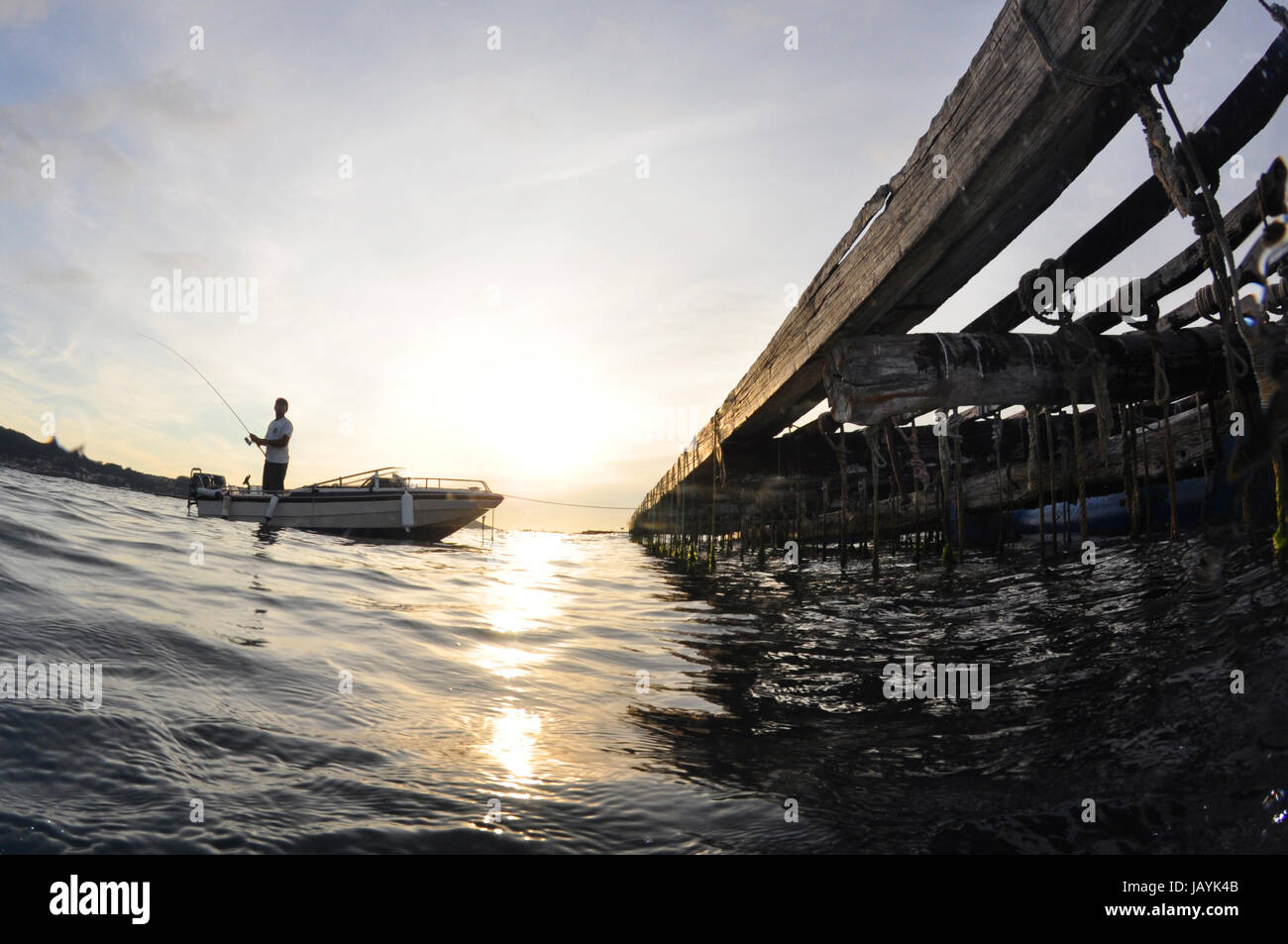 Entspannendes Fischen in der Nähe einer Muschel Floß bei Sonnenuntergang Stockfoto