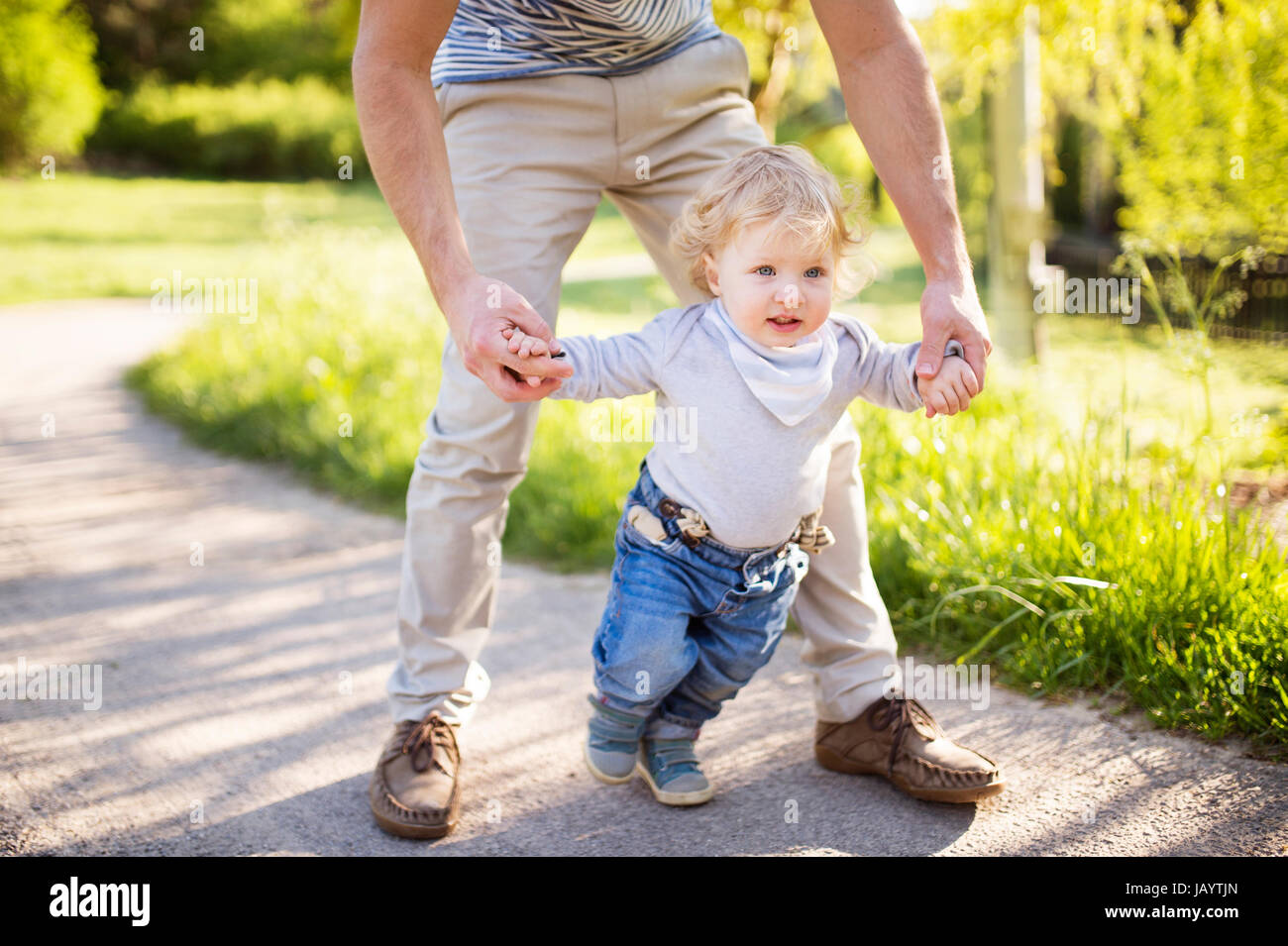 Nicht erkennbare Vater Hand in Hand seines Sohnes unternimmt erste Schritte Stockfoto