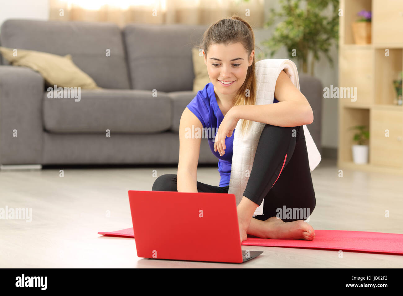 Fitness-Frau Auswahl Tutorial vor dem Training auf dem Boden im Wohnzimmer zu Hause sitzen Stockfoto