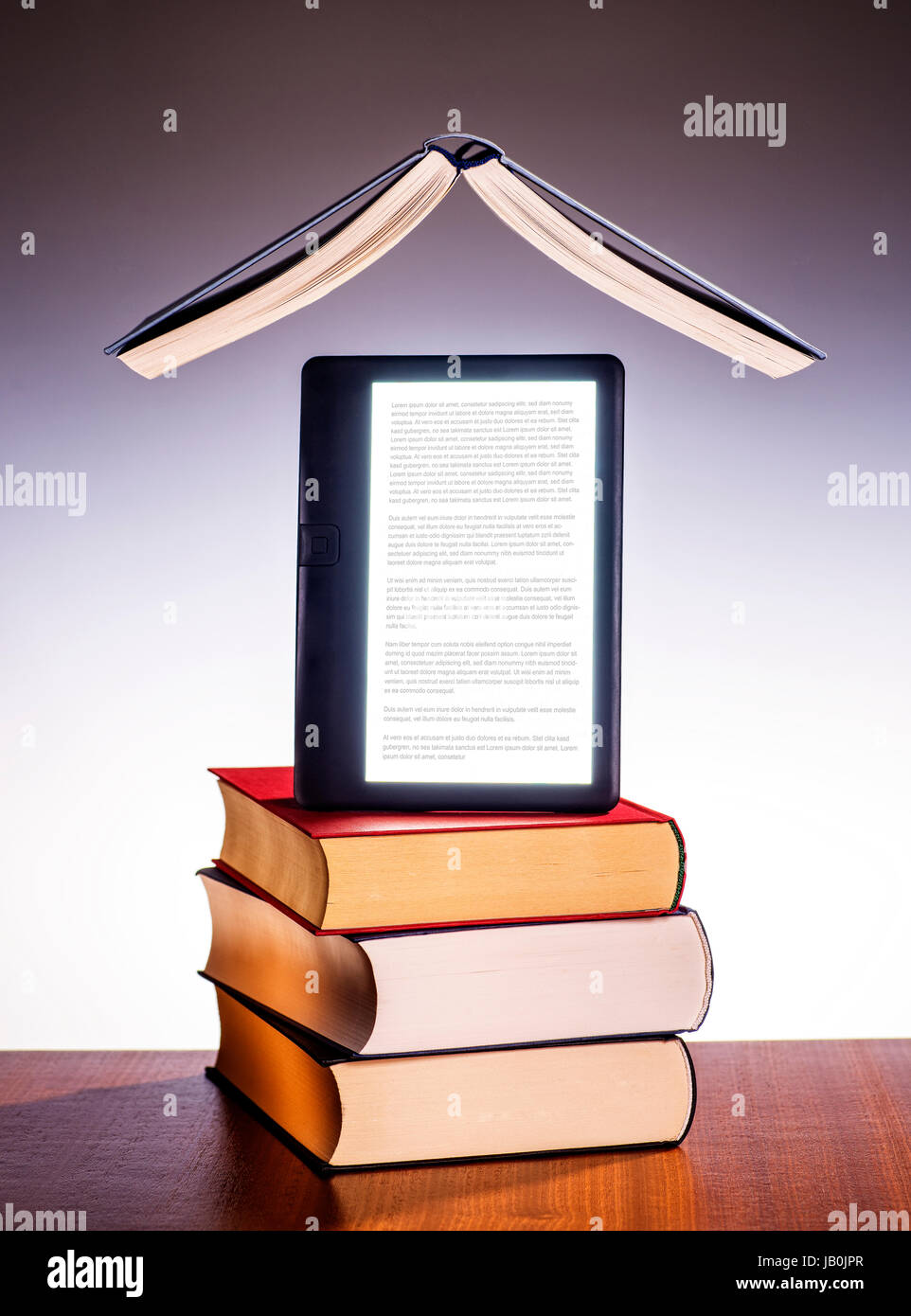 Offenes Buch schwebt über einem Stapel von gedruckten Büchern und e-Book. Stockfoto