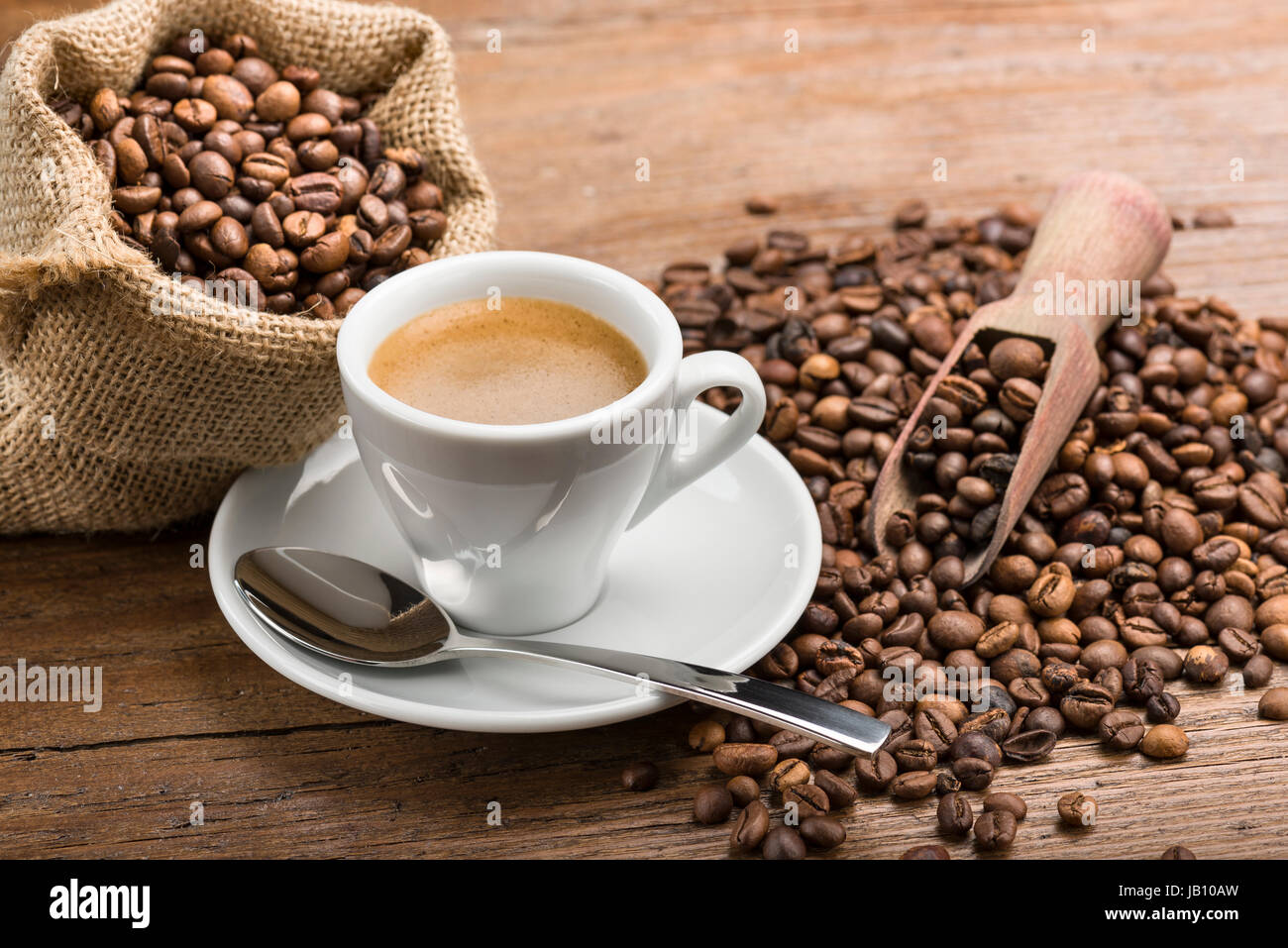 Tasse Kaffee mit Kaffeebohnen auf Holztisch Stockfoto