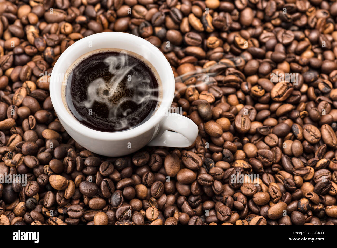 Tasse dampfenden Kaffee auf Haufen von gerösteten Kaffeebohnen Stockfoto