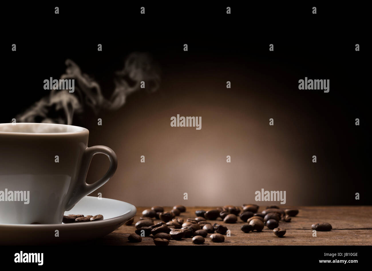 Tasse dampfenden Kaffee auf Holztisch mit gerösteten Kaffeebohnen. Stockfoto