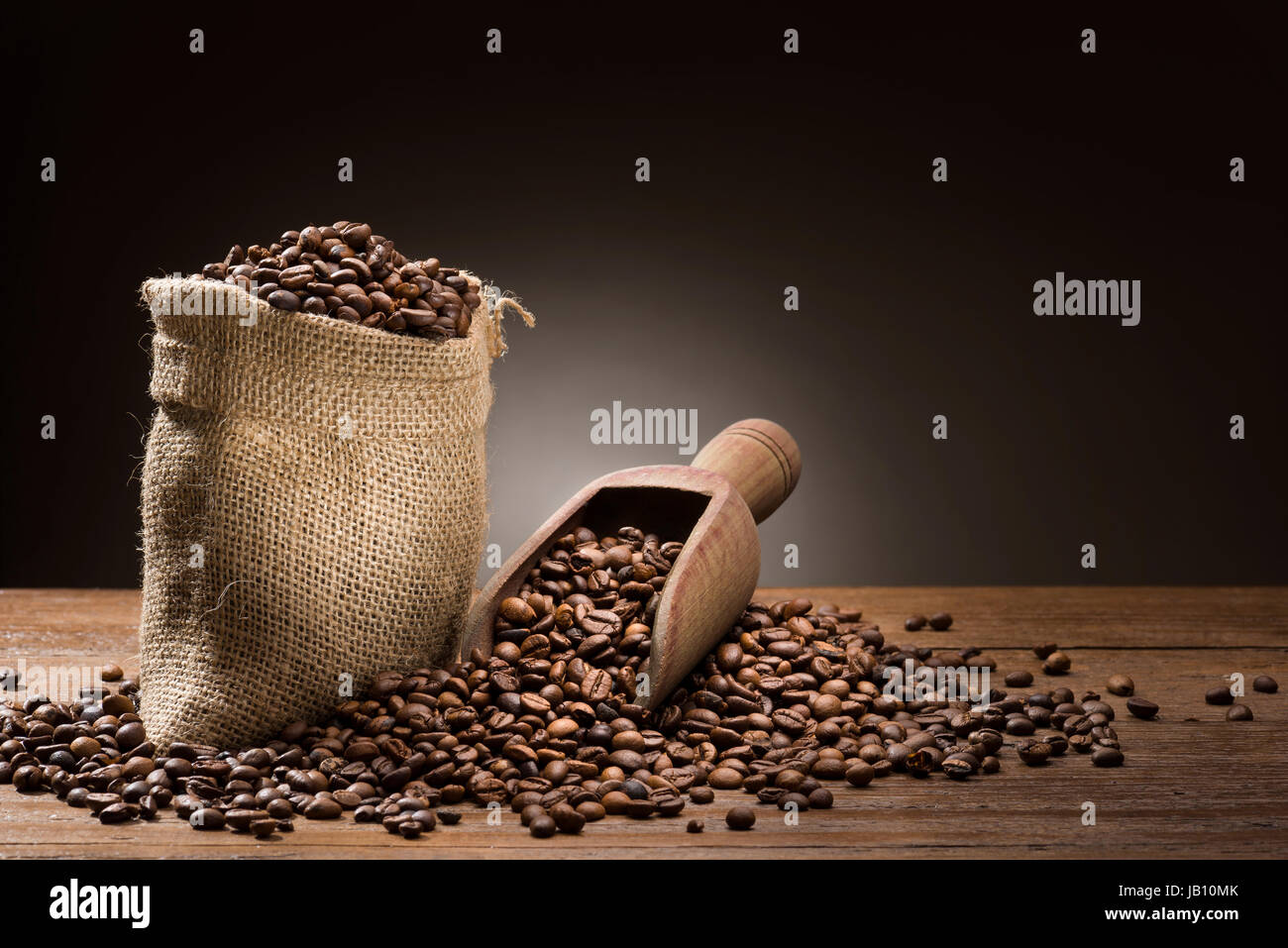 Haufen von Kaffeebohnen mit Leinensack und hölzerne Schaufel auf Tabelle. Stockfoto