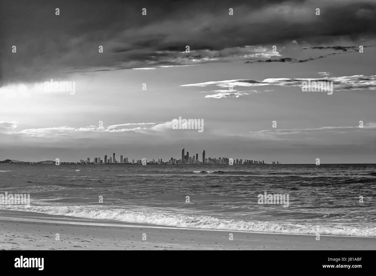 Die Skyline von der Gold Coast City gesehen vom Strand in Coolangatta, Queensland, Australien. Die Abendsonne wirft lange Schatten auf den Wellen. Stockfoto