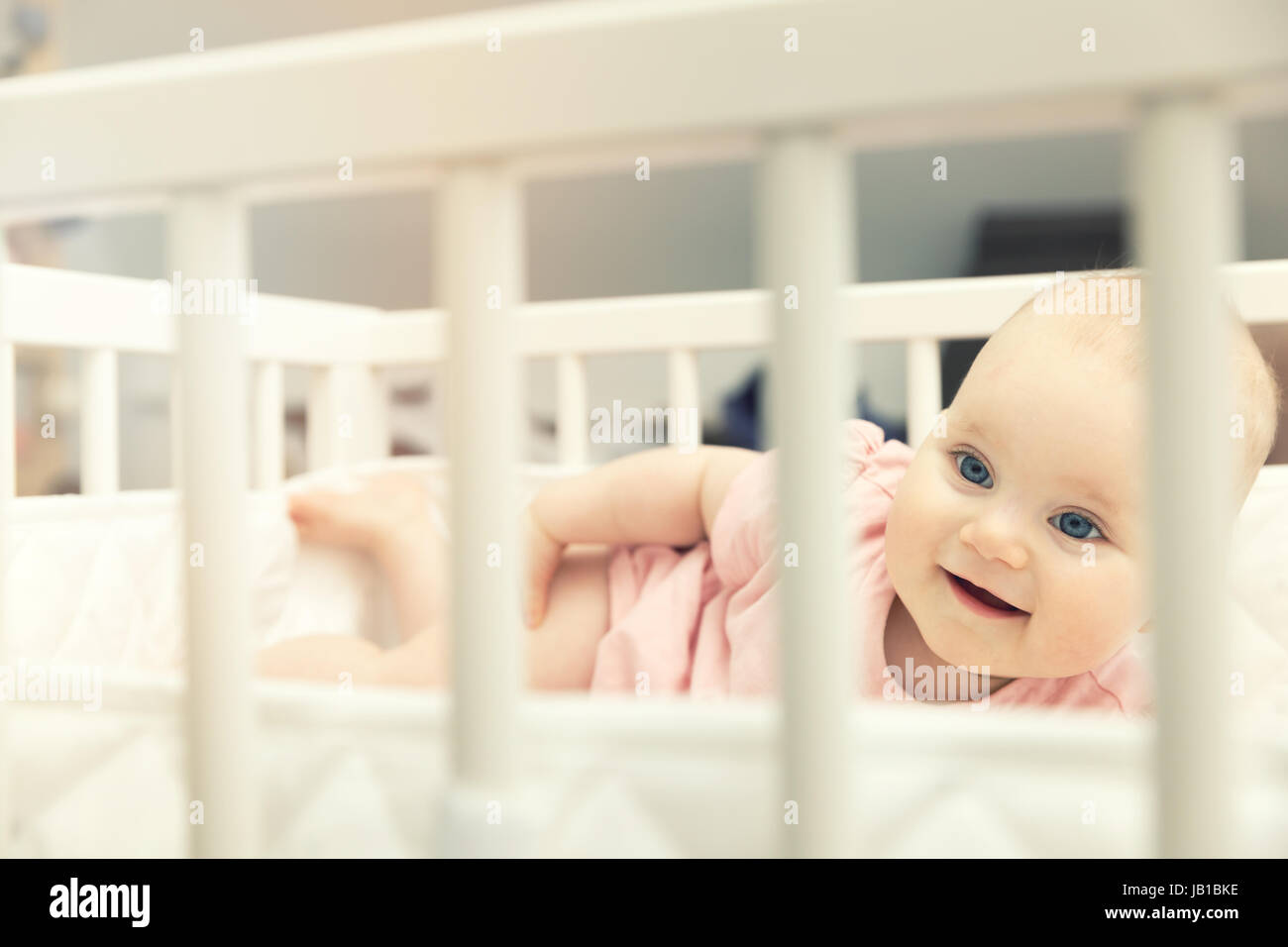 lächelndes Baby Babymädchen in Krippe zu Hause liegen Stockfoto