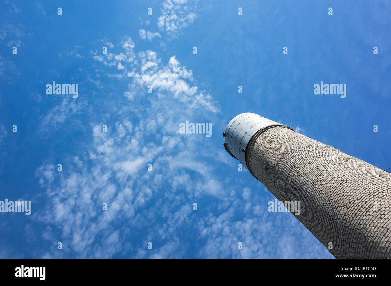 Hohen Wasserturm machte der grauen Ziegel mit Stahltank oben über bewölkten blauen Himmelshintergrund Stockfoto