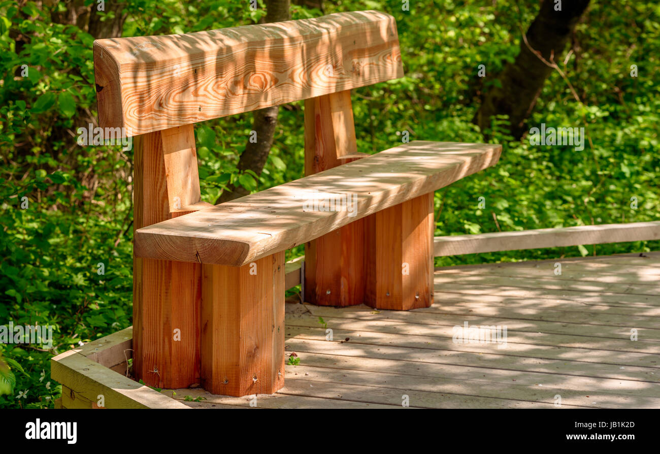 Holzbank auf Holzsteg. Spiel des Lichtes auf Boden und Möbel. Stenshuvud Nationalpark in Schweden. Stockfoto