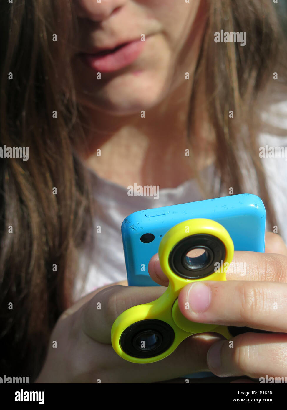 Zappeln Sie Spinner Spielzeug und iPhone 5 s in der Hand der Jugendlichen Stockfoto