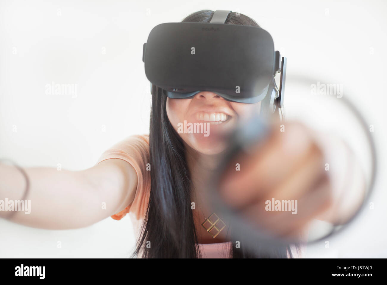 Junge asiatische Frau mit Virtual Reality headset Oculus Rift und demonstrieren, wie der Touch Control zu verwenden Stockfoto