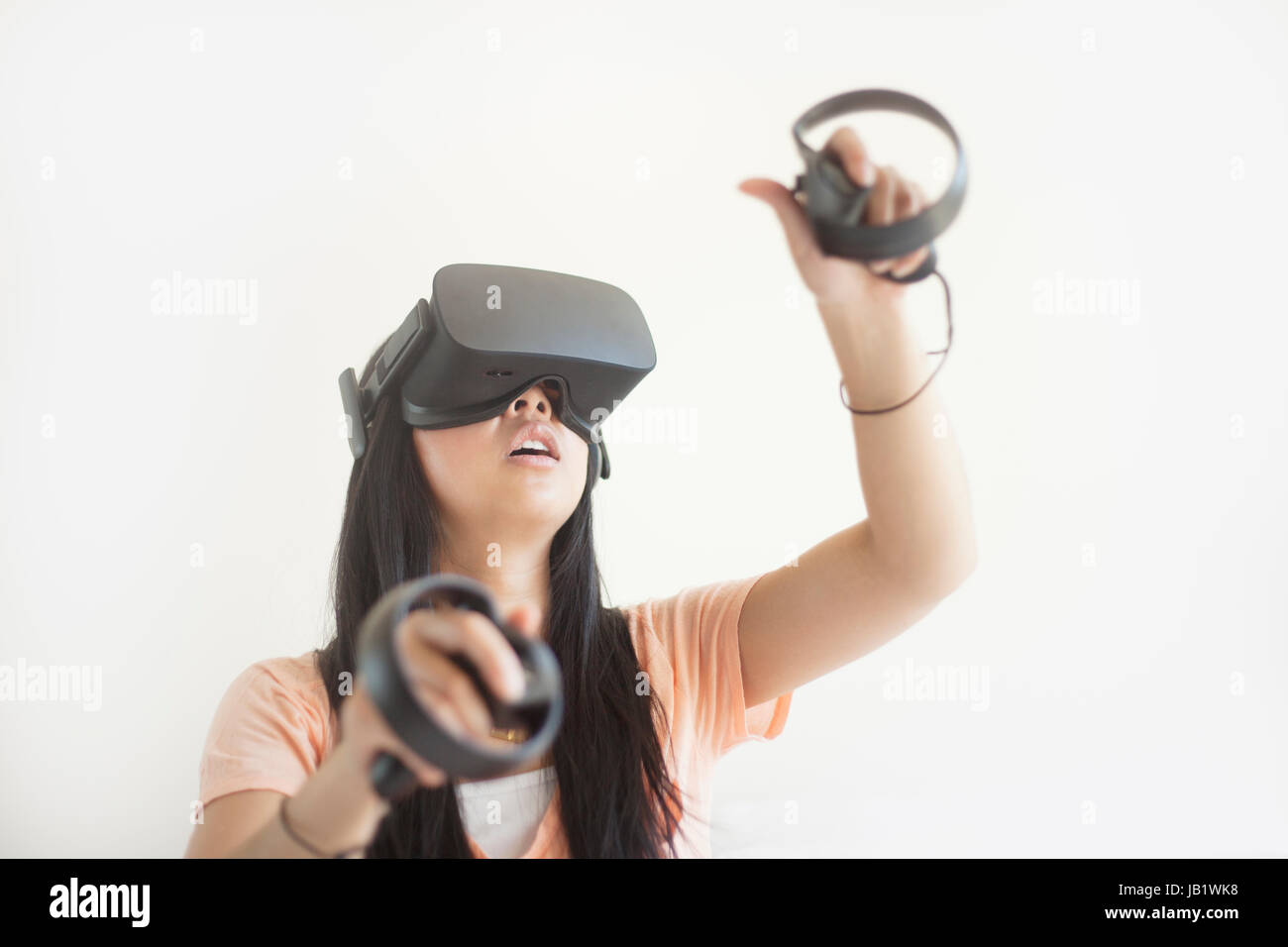 Junge asiatische Frau mit Virtual Reality headset Oculus Rift und demonstrieren, wie der Touch Control zu verwenden Stockfoto