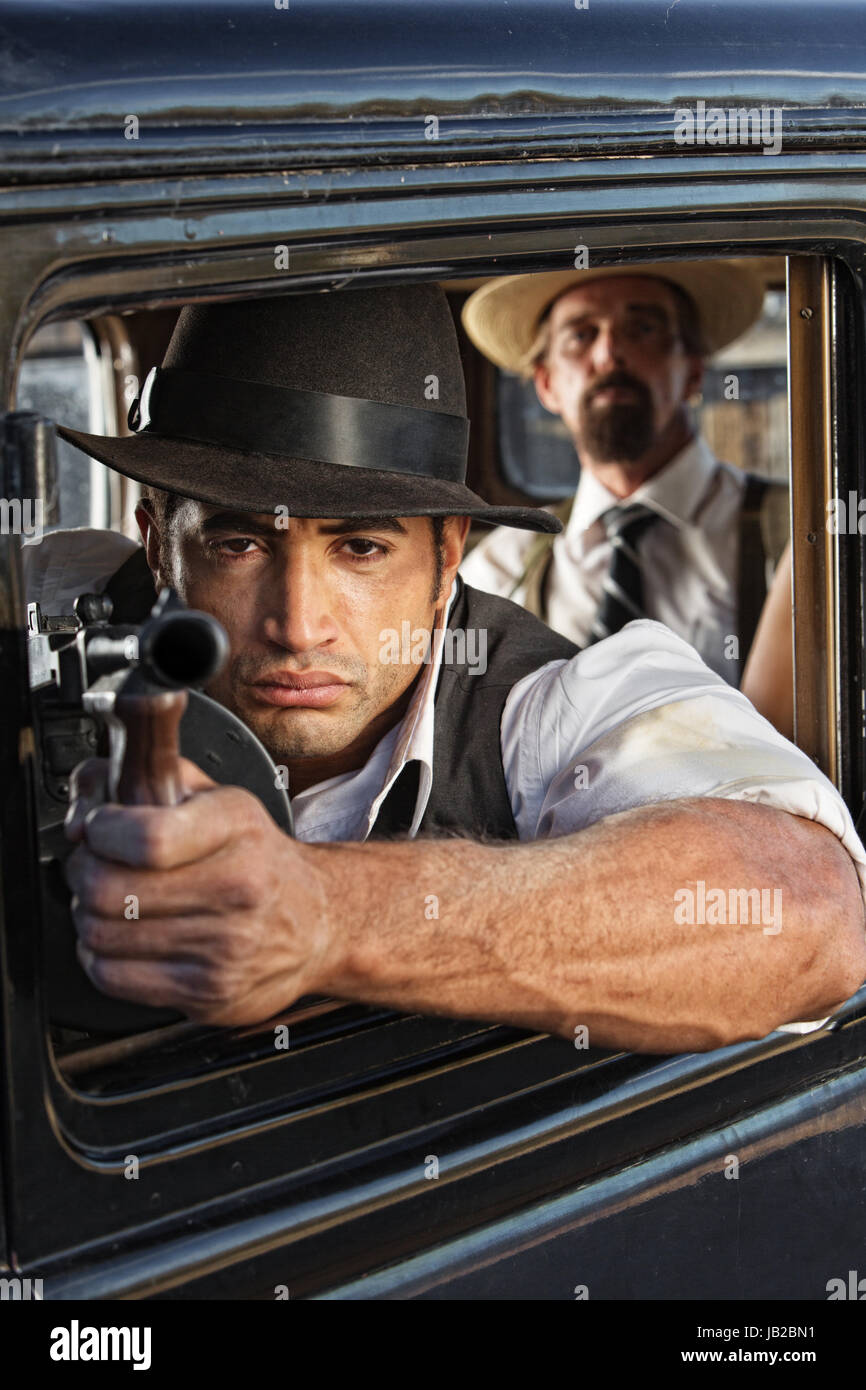 1920er Jahre Vintage Gangster schießen Maschinenpistole aus Auto Stockfoto