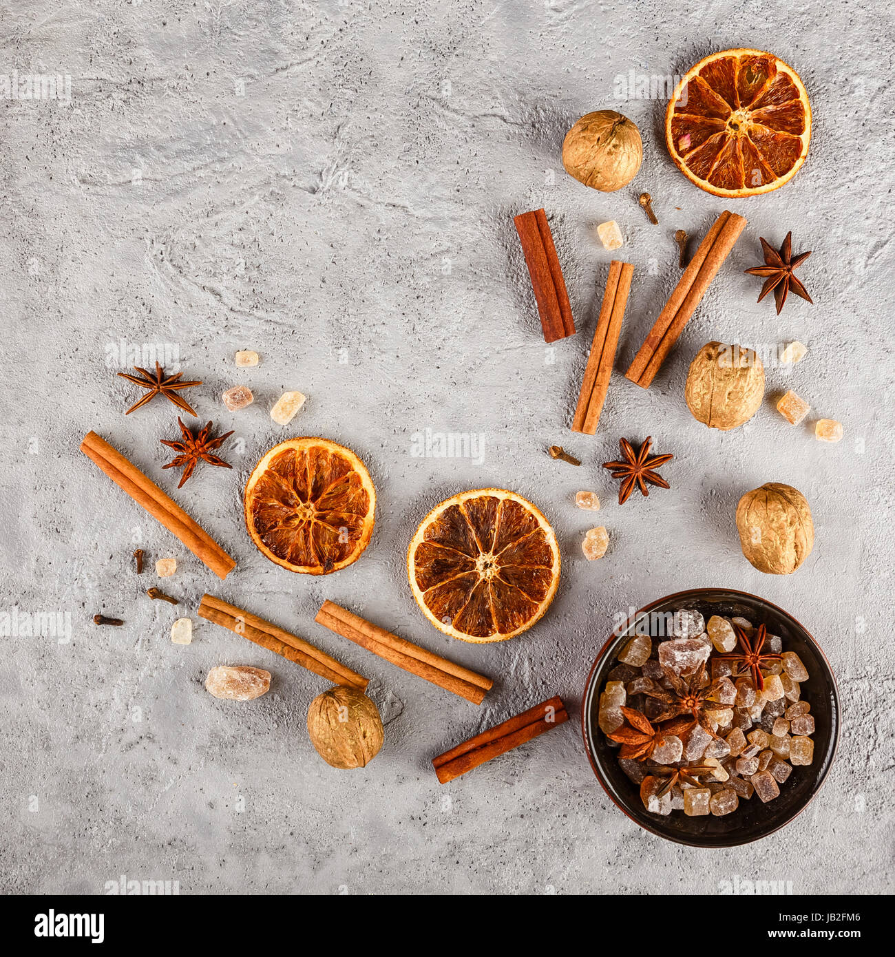 Verschiedene Arten der Gewürze - Zimt, Nelken, Anis Sterne, Walnüsse, getrocknete Orangenscheiben, karamellisierten braunen Zucker auf grauem Beton Hintergrund. Top vi Stockfoto