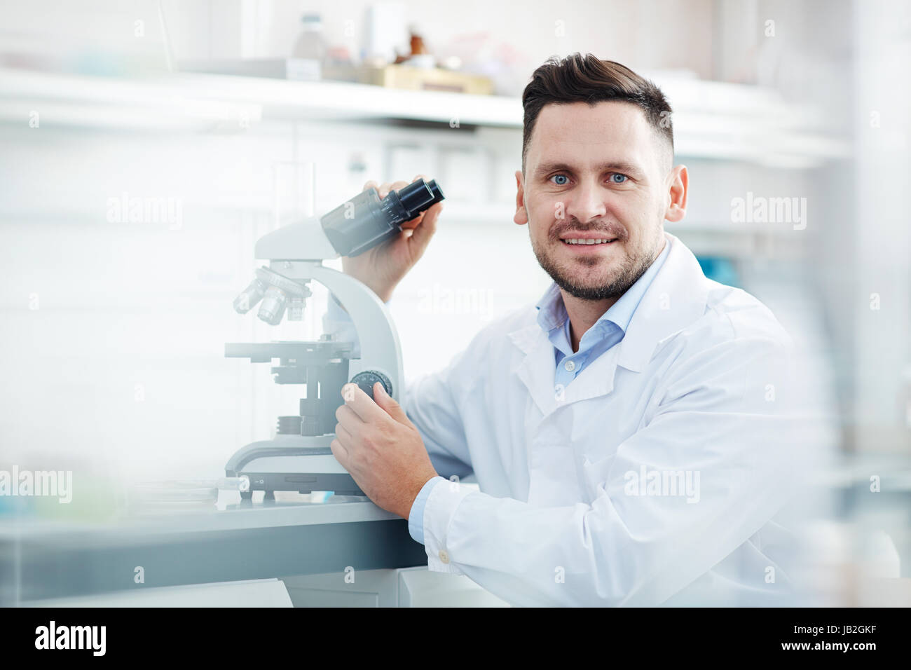 Lächelnde Wissenschaftler Mikroskop im Labor Stockfoto